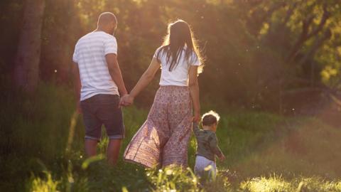 File image of two adults and a child walking outside