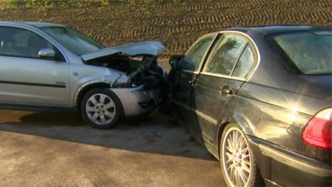 Emergency services and actors reconstruct the scene of a head-on collision.