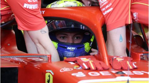 Oliver Bearman in the cockpit of his Ferrari with the visor on his helmet raised