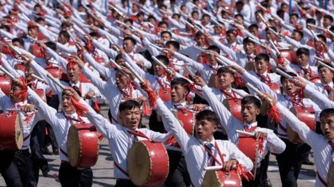 Students march past a balcony from where North Korea's leader Kim Jong Un was watching