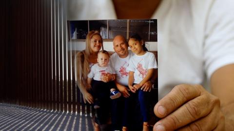 Adrian Meza holds up a photo of his family