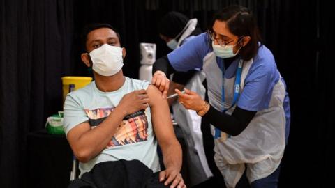 A health worker gives someone a vaccine in London