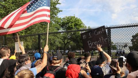 Demonstrators gather in front of a fence surrounding Lafayette Park outside the White House