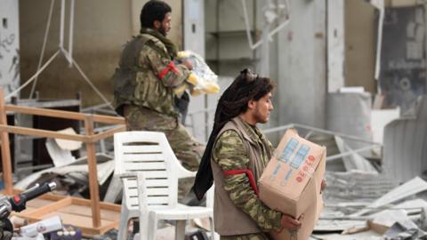 Turkish-backed Syrian rebel fighters loot a shop in the Syrian city of Afrin (18 March 2018)