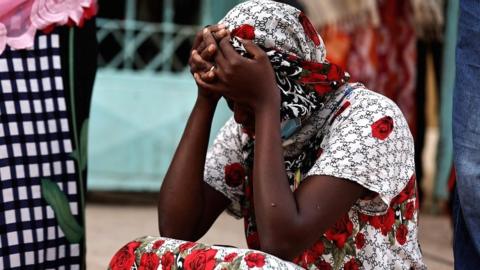 Kaba, a mother of a 10-day-old baby, reacts as she sits outside the hospital on 26 May.