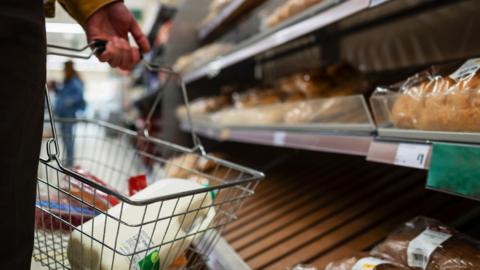 A person shops for milk and bread in a supermarket