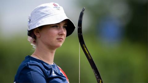 Archer Penny Healey wearing a Team GB bucket hat and holding a bow