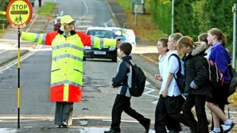 Lollipop crossing patrol lady guides school children across the road