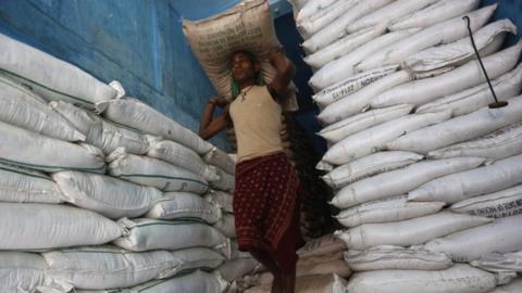 A labourer carries a sack filled with sugar in a store at a wholesale market in Kolkata, India, February 15, 2016