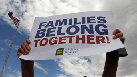 Protesters against Trump's immigration policy hold a sign that reads "Families Belong Together"