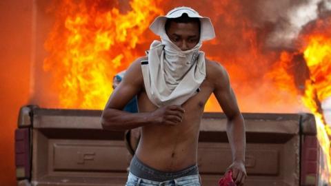 A person runs during clashes between opponents of Venezuelan President Nicolas Maduro and members of the Bolivarian National Guard of Venezuela