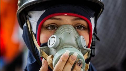 A demonstrator wears a tear gas mask during opposition protests in Caracas, Venezuela, 19 April 2017.