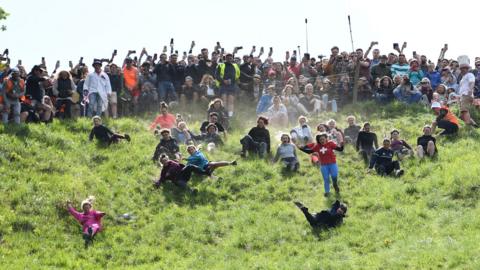 Cheese rolling competitors falling down Cooper's Hill near Gloucester
