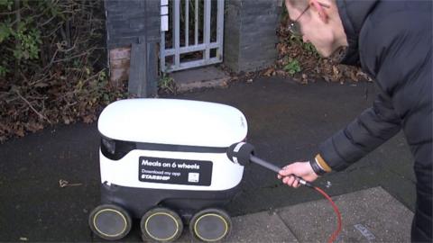 Reporter trying to interview food delivery robot