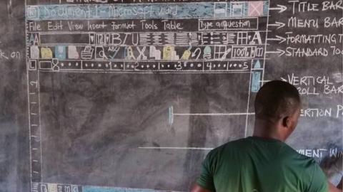 A man is seen putting the finihsing touches to an illustration on a blackboard: it is the interface for Microsoft's Word programme, with earch main function labelled.