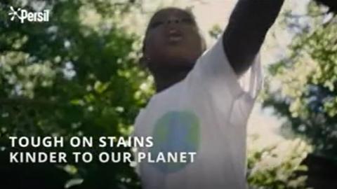 Screen grab of Persil advert showing young boy in background as text reads 'Tough on stains and kinder to our planet'