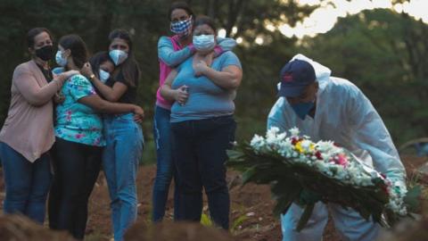 Relatives of a coronavirus victim mourn as their loved one is buried at the Vila Formosa cemetery in Sao Paulo, Brazil, on March 31, 2021