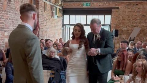 Woman helped down aisle by man.
