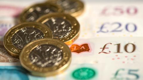 A number of one pound coins on top of some cash notes