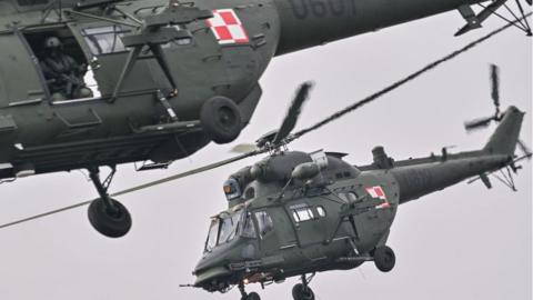 Polish helicopters fly over soldiers in their tanks while crossing the Vistula River during the DRAGON-24 NATO military defense drills on March 04, 2024