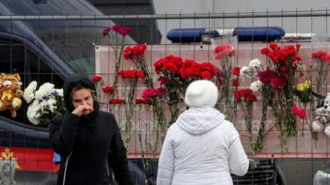 People bring flowers to the burned Crocus City Hall concert venue following a terrorist attack in Krasnogorsk, outside Moscow, Russia, 23 March 2024.
