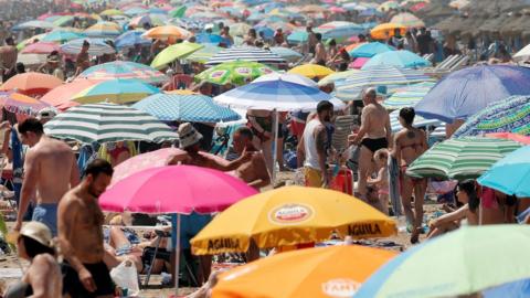 A packed Malvarrosa beach during a hot day in Valencia, Spain