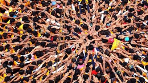 Indian Hindu devotees gesture before attempting to form a human pyramid in a bid to reach and break a dahi-handi (curd-pot) suspended in air during celebrations for the Janmashtami festival, which marks the birth of Hindu god Lord Krishna, in Mumbai on August 18, 2014