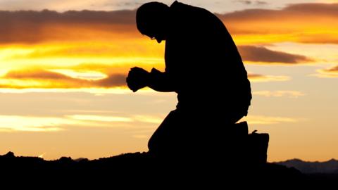 Man praying in silhouette