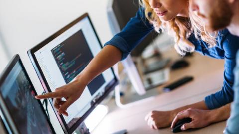 Two people examine computer code on a screen