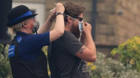 Community Police Officer helps man put on a dust mask