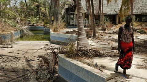 A Senegalese woman walks near an abandoned hotel