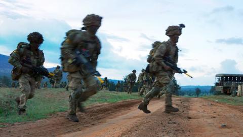 Soldiers run across a road during a simulated military exercise of the British Army Training Unit in Kenya (BATUK) together with the Kenya Defence Forces (KDF) March 26, 2018.