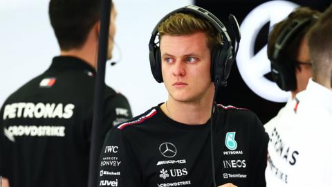 Mick Schumacher on the sideline with intercom headphones on