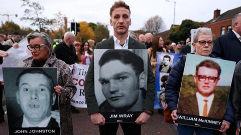 amily members hold pictures of victims of the 1972 'Bloody Sunday', as a judge is expected to give a verdict on the trial of the British army veteran known as 'Soldier F', charged with two murders and five attempted murders in relation to Bloody Sunday, in Belfast, Northern Ireland, October 23,