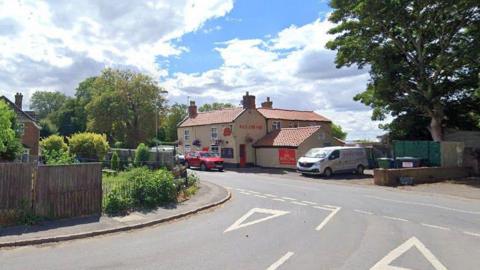 Google shot of junction at start of Gaysfield Road. There is a pub in the background, along with trees and hedges.