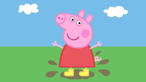 Peppa Pig a cartoon pig wearing a red dress and wellies stands in a muddy puddle 