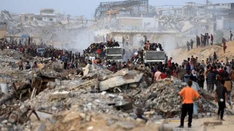 Palestinians climb onto trucks carrying aid supplies that entered Gaza through Israel, in Beit Lahia, in the northern Gaza Strip.