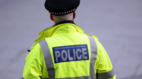 A back view of a policeman wearing a yellow police jacket.