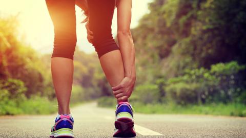 Close-up of a woman wearing exercise gear holding her ankle