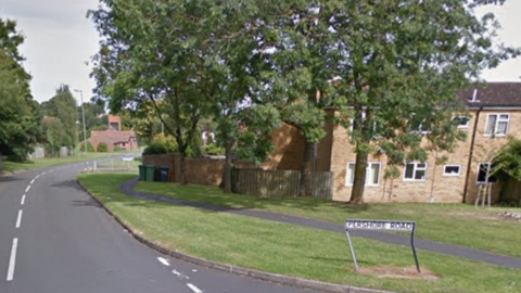 A street sign on a corner reads Pershore Road. Terraced houses, trees and grass verges are behind it.