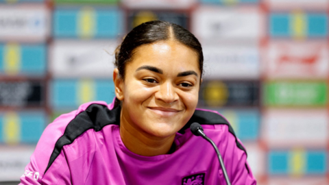 Jess Carter wearing a pink England training top during a press conference.