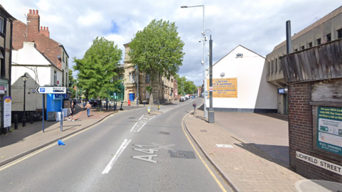 Google Streetview image of Lichfield Street in Bilston. Businesses and other buildings flank the road, with a sign on the left pointing to a car park