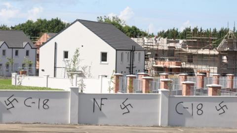 The perimeter wall of a new estate was daubed with swastikas and Combat 18 signs