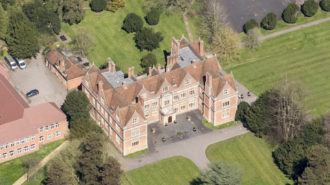 An aerial view of Shaw House, an Elizabethan mansion, and surrounding grounds, and a neighbouring building to its left. 