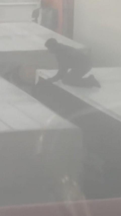 Man on top of lorry with other lorries surrounding it in foggy conditions