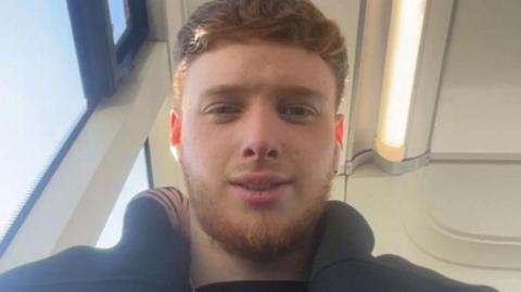 Brandon Kershaw has thick ginger/brown hair shaved down the sides of his head. He also has a beard.