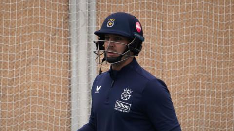 Delano Potgieter stands in the nets during a training session with Hampshire, wearing a helmet