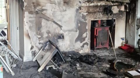 Extensive smoke damage can be seen in a living room inside a house