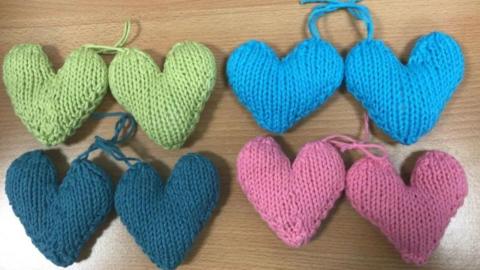 Four pairs of knitted hearts, one pair is light green, one light blue, one dark blue and the other is pink