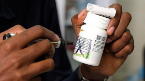 A staff member holds antiretroviral medication at TASO Mulago service center on February 17, 2025 in Kampala, Uganda.